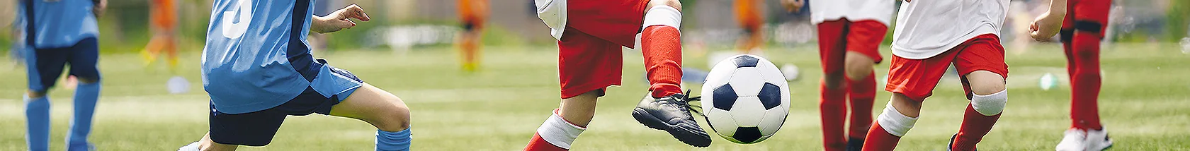 芝生のグラウンドでサッカーの試合をする子どもたち