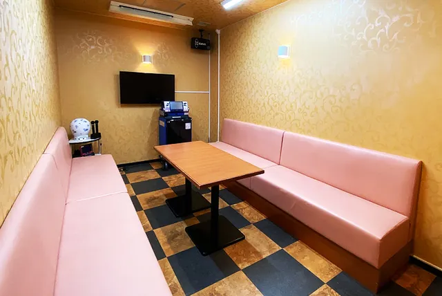 ピンクのソファが向かい合うカラオケルーム