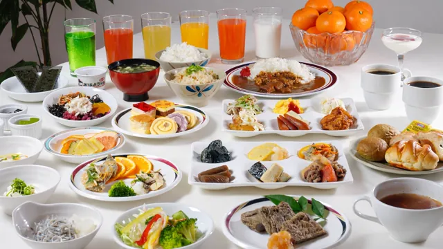 朝食ビュッフェの料理の数々。カレーやパン、小鉢の和食、色とりどりのジュースとみかん