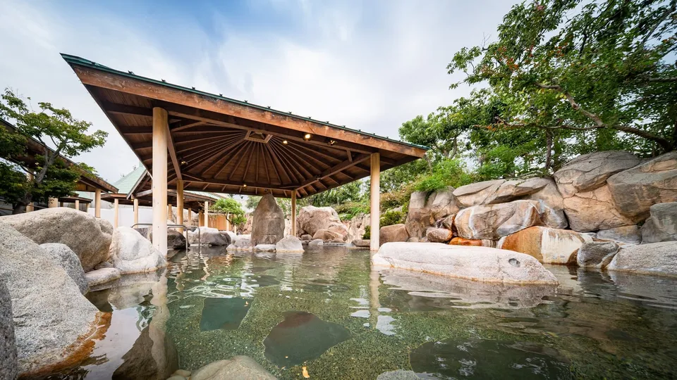 A large open-air bath ringed by mountains and fields